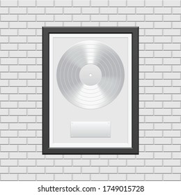 Silver vinyl record with black frame on white brick wall
