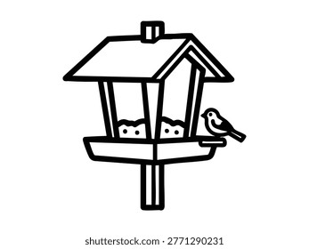 A simple black and white line art illustration depicts a bird feeder filled with seeds, with a small bird perched on its edge, ready to eat. The feeder features a classic house-like structure with a roof, standing on a post, offering sustenance to wildlife.