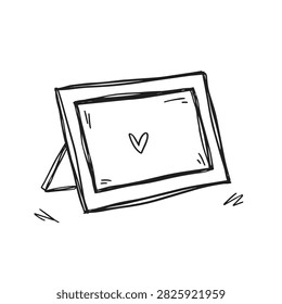 A simple black and white line drawing of a standing picture frame featuring a small heart icon in the center isolated on white