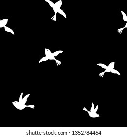 Simple graphic monochrome seamless repeat pattern with little white birds flying on a black background 