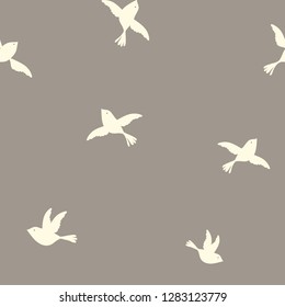Simple minimalistic seamless repeat pattern with flying birds silhouettes on tan background
