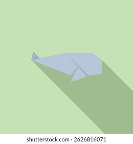 Simple origami whale folded from blue paper casting a long shadow