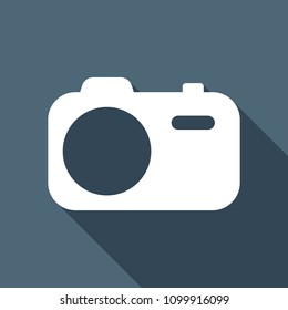 Simple photo camera. Technology icon. White flat icon with long shadow on background