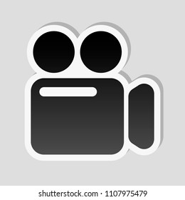 Simple video camera icon. Sticker style with white border and simple shadow on gray background
