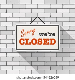 Simple white sign with text 'Sorry we're closed' hanging on a gray brick wall. Grunge brickwork background, textured rough surface. Creative business interior template for shop, store, supermarket.