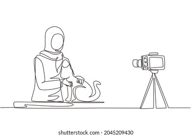 Single continuous line drawing Arabian vet blogger sitting in front of camera with cats and recording video blog about animals. Zoo psychologist creating content for vlog one line draw design vector