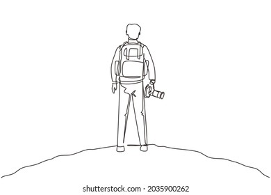 Single continuous line drawing back view man holding camera standing cliff mountain in forest landscape view and sunset  Young tourist photographer  One line draw design vector illustration