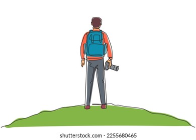 Single continuous line drawing back view man holding camera standing on cliff of mountain in forest landscape view with sunset. Young tourist photographer. One line draw design vector illustration
