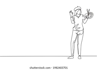 Single continuous line drawing female painter stands with gesture okay using hat and painting tools to produce artwork in his workshop studio. Dynamic one line draw graphic design vector illustration