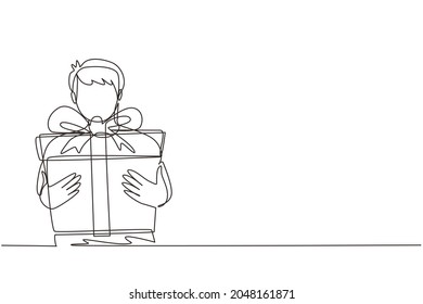 Single continuous line drawing kid holding big ribbon bow wrapped gift box in front of his in arms. Little boy carries holiday gift box with bow in his hands. One line draw design vector illustration