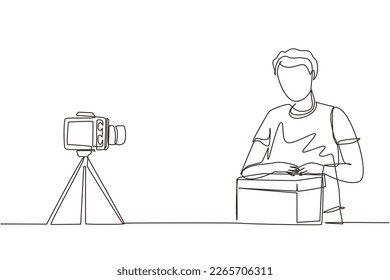 Single continuous line drawing male vlogger unbox and review product live on youtube in studio. Social media influencer recording unboxing video at home. One line draw design vector illustration