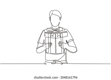 Single continuous line drawing man holding big ribbon bow wrapped gift box in his arms. Young male holding a gift. Guy with a gift box. Gift for the holiday. One line draw design vector illustration