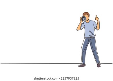 Un fotógrafo de dibujo de línea continua de pie, con gesto de pulgares hacia arriba, sujetando la cámara fotográfica y fotografiando. profesión o ocupación creativa. ilustración vectorial de diseño gráfico de una línea