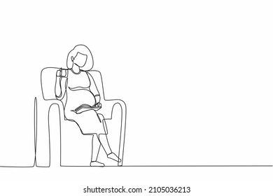 Single continuous line drawing pregnant young woman sitting on sofa, reading book and drinking tea. Cozy evening with hot drink. Outside the winter. One line draw graphic design vector illustration