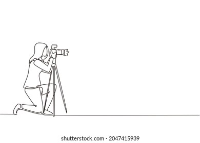 Single continuous line drawing professional photographer woman kneeling for taking pictures with digital camera and tripod. Digital photography hobby for girl. One line draw design vector illustration