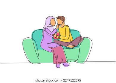 Single continuous line drawing romantic Arabian couple sitting relaxed together on sofa, woman feeding popcorn to man. Celebrate wedding anniversary. One line draw graphic design vector illustration