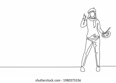 Single continuous line drawing woman painter stands with a thumbs-up gesture using a hat and painting tools to produce artwork in her workshop studio. One line draw graphic design vector illustration