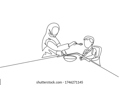 Single continuous line drawing of young Islamic mother feeding healthy food to son using spoon at home. Arabian muslim happy family motherhood concept. Trendy one line draw design vector illustration