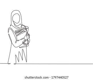 Single continuous line drawing of young female muslim businesswoman carrying annual report books to business meeting. Arab middle east cloth hijab and veil. One line draw design vector illustration