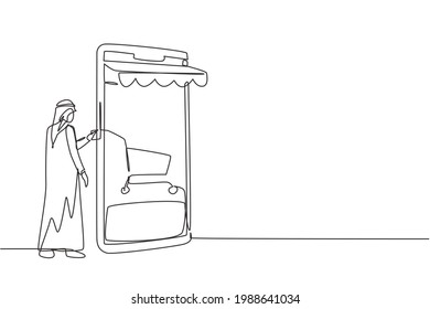 Single continuous line drawing young Arab man inserting credit card into canopy smartphone screen with shopping cart. Digital payment concept. Dynamic one line draw graphic design vector illustration