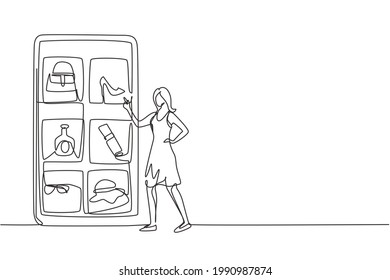 Single continuous line drawing young woman choosing shopping items on a giant smartphone screen. Digital lifestyle with internet and gadgets. Dynamic one line draw graphic design vector illustration