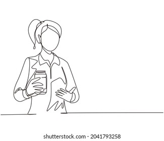 Single continuous line drawing young woman holding and showing soda refreshing a can sitting on couch in living room at home. Girl holds refreshing soda drink. One line draw design vector illustration