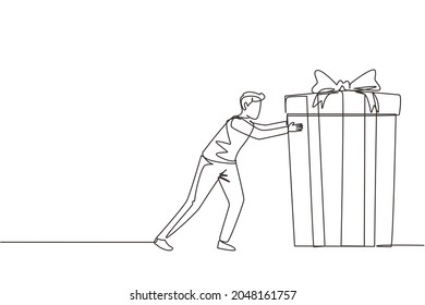 Single continuous line drawing young man pushes in front of him huge gift . Giving gifts for holiday concept. Wrapped birthday gift box with bow. Present, gift, birthday. One line draw design vector