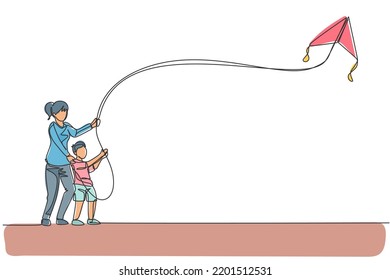 Single continuous line drawing of young mom and her son playing to fly kite up into the sky at outdoor field. Happy family parenthood concept. Trendy one line draw design vector graphic illustration