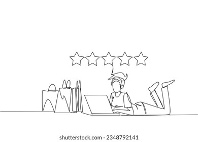 Single continuous line drawing young smiling woman on stomach while typing on laptop. Next to the laptop is a shopping bag. Give the best review with pleasure. One line design vector illustration