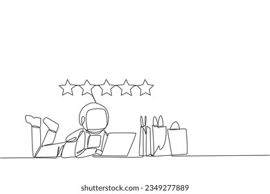 Single continuous line drawing young astronaut on stomach while typing on laptop. Next to the laptop is shopping bag. Give the best review with pleasure. Spaceman. One line design vector illustration
