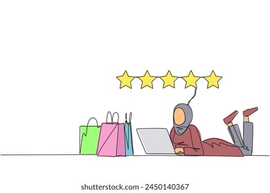 Single continuous line drawing young Arabian woman on stomach while typing on laptop. Next to the laptop is a shopping bag. Give the best review with pleasure. One line design vector illustration