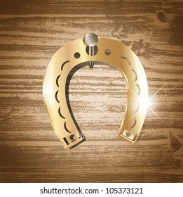 Single golden horseshoe over wooden background