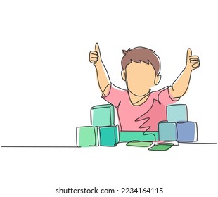 Single line drawing of young happy boy playing stack of puzzle block on table and giving thumbs up gesture in kindergarten class. Business deal continuous line draw design graphic vector illustration