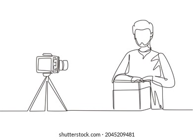 Single one line drawing Arab male vlogger unboxing, review product live on youtube in studio. Social media influencer recording unboxing video at home. Continuous line draw design vector illustration