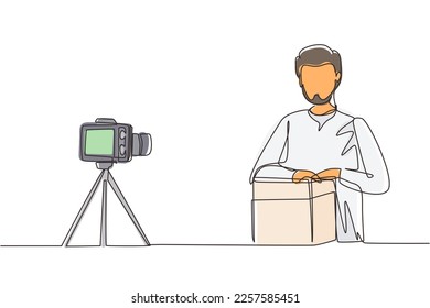 Single one line drawing Arab male vlogger unboxing, review product live on youtube in studio. Social media influencer recording unboxing video at home. Continuous line draw design vector illustration