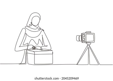 Single one line drawing beauty Arabic female show unboxing received package in live at home. Woman vlogger unboxing product, recording review on camera. Continuous line draw design vector illustration