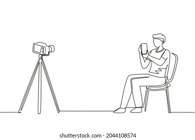 El blogger de dibujo de una sola línea revisa y prueba el nuevo smartphone con la cámara dslr. Transmisión en directo en el canal. Hombre portando un teléfono móvil para el producto de revisión. Ilustración vectorial de dibujo de línea continua