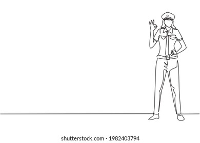 Single one line drawing of female pilot stands with gesture okay and complete uniform serves airplane passengers fly to destination. Modern continuous line draw design graphic vector illustration