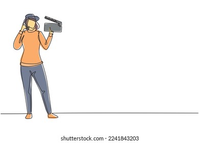 Single one line drawing female film director stands with call me gesture holding clapperboard and prepare camera crew for shooting at studio. Continuous line draw design graphic vector illustration