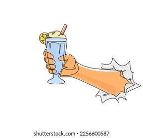 Single one line drawing hand holds glass milkshake with whipped cream through torn white paper. Cold soft drink for summer. Sweet beverage. Tasty and yummy fast food continuous line draw design vector