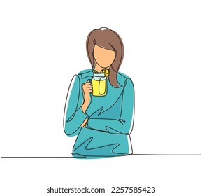 Single one line drawing pretty woman holds mug of fruit-berry lemonade with ice in hand. Young girl wearing shirt having morning breakfast with orange juice. Continuous line draw design graphic vector