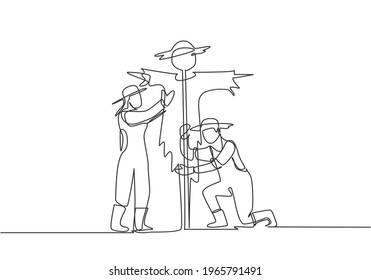 Single one line drawing of young couple farmer is installing a scarecrow to ward off pest birds. Farming challenge minimal concept. Modern continuous line draw design graphic vector illustration.