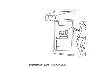 Single one line drawing young woman inserting credit card into canopy smartphone screen with shopping cart. Digital payment concept. Modern continuous line draw design graphic vector illustration