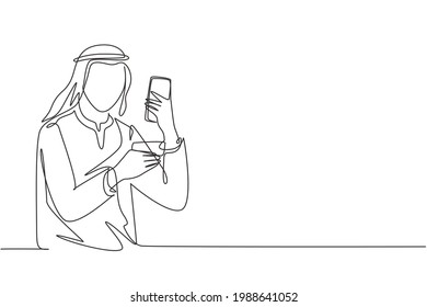 Single one line drawing young Arab man typing entering credit card code on smartphone around desk. Digital lifestyle and payment concept. Modern continuous line draw design graphic vector illustration