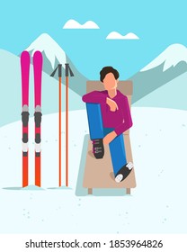 Skier sitting on a sun lounger. Nearby, skis and sticks are stuck in the snow. Blue sky and mountains in the background.