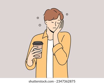 Sleepy man with disposable cup of coffee feels exhausted and lacks strength due to lack of sleep. Guy sleeps on go and tries to cheer up with takeaway coffee with high content of caffeine and taurine