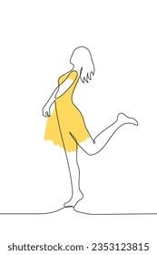 slender woman in a yellow dress silhouette stands in full growth playfully raising her leg - one line art vector. the concept summer dress, female attractiveness, spring mood