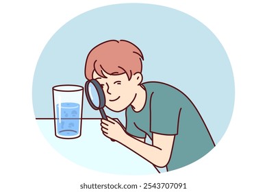 Small boy examines water in glass through magnifying glass, studying chemical composition liquid or looking for microbes. Teenage child curiously studies water, wanting to work in chemical laboratory