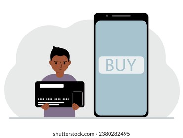 A small boy holds a credit card in his hand and a large mobile phone nearby. The concept of bank payment, online purchase, children's credit card.