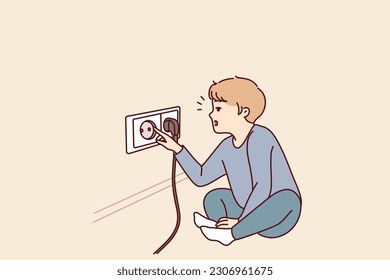 Small boy sticks fingers into socket, playing with electrical equipment and risking electric shock. Preschool child with curiosity pulls fingers to electrical socket and needs attention of parents